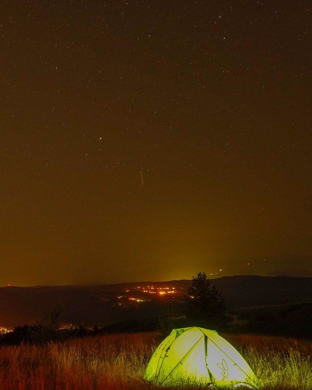 Glowing tent under the Milky Way, Sofia's lights in the valley below